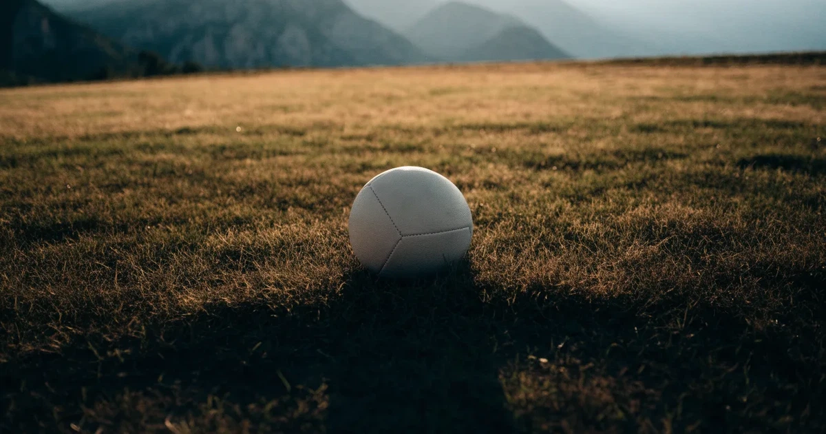 Ein Fussball auf einem staubigen Rasenstück in der Abendsonne, im Hintergrund eine hohe Bergkette